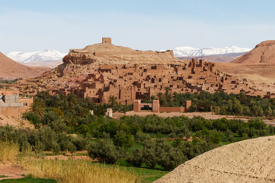Fortified city of Ait Benhaddou along the former caravan route between the Sahara and Marrakech in Morocco with snow covered Atlas mountain range in background