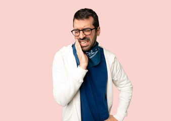 Handsome man with glasses with toothache on isolated pink background