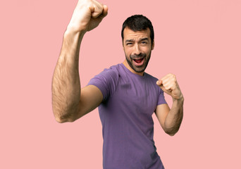 Fototapeta premium Handsome man celebrating a victory on isolated pink background