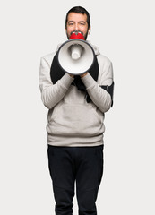 Sport man shouting through a megaphone to announce something over isolated grey background