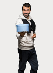 Fototapeta premium Sport man holding a gift in hands over isolated grey background