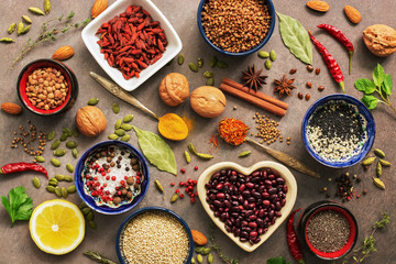 Super food background, a variety of cereals, legumes, spices, herbs, nuts. Various seasonings for cooking on brown background. Top view, copy space.