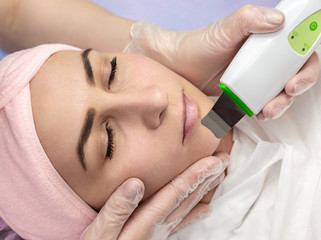 Fototapeta premium Woman receiving cleansing therapy with professional ultrasonic equipment in beauty salon. Face Skin Care.