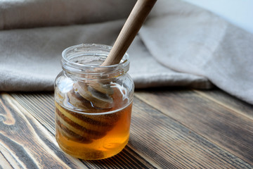 Honey in a transparent jar with a honey spoon