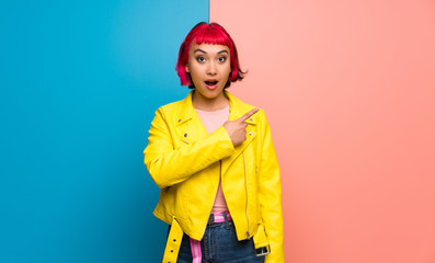 Young woman with yellow jacket surprised and pointing side