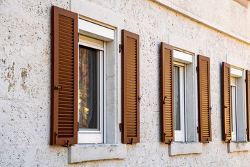 House facade with two windows with old wooden shutters with slats