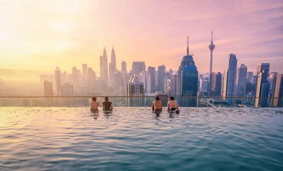 Foto op Plexiglas Reiziger op zoek naar de skyline van de stad Kuala Lumpur in het zwembad op het dak van het hotel bij zonsopgang in Kuala Lumpur, Maleisië. © nuttawutnuy