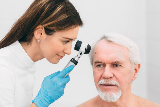 Doctor examining patient skin moles with dermoscope