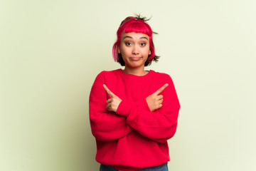 Young woman with red sweater pointing to the laterals having doubts