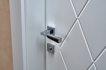 Fototapeta na wymiar Contemporary white door with shiny handle in bathroom