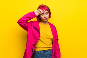 Young woman with pink hair over yellow wall with tired and sick expression