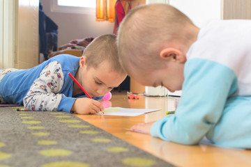 Cute little boys drawing a story with colorful pens and crayons at home. Selective focus.