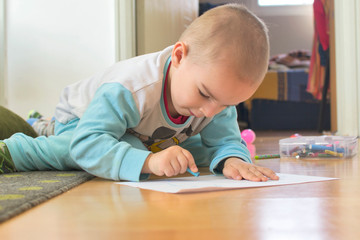 Naklejka premium Cute little kid boy drawing a story with colorful pens at home.