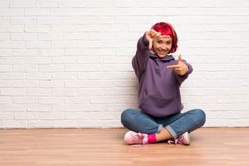 Young woman with pink hair sitting on the floor focusing face. Framing symbol