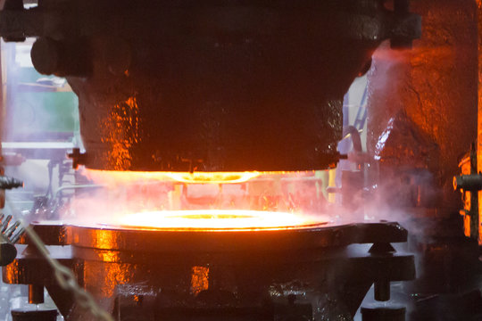 Steel press rolling industrial workshop. Hot iron stamping of train and wagon wheels. Industrial details of metallurgic factory or plant.
