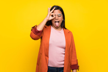 Young Colombian girl over yellow wall makes funny and crazy face emotion