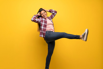 Young Colombian girl over yellow wall jumping