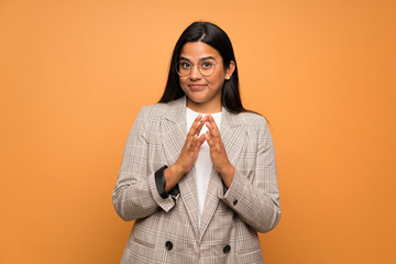 Young Colombian girl over brown wall scheming something