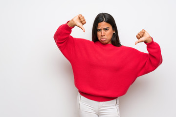 Young Colombian girl with red sweater showing thumb down