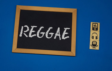 inscription REGGAE on a black board with a blue background with three wooden cubes