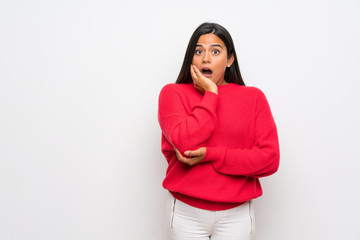 Young Colombian girl with red sweater surprised and shocked while looking right