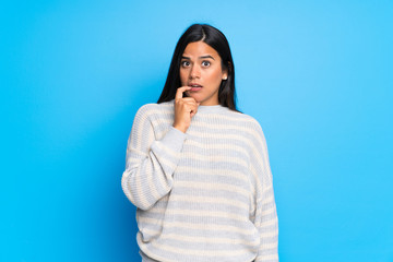 Young Colombian girl with sweater having doubts while looking up