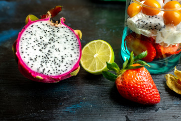 fresh fruit of strawberries, among them beautiful, pink dragon fruit, next to the dessert made of...