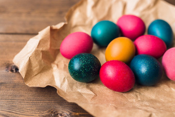 painted colorful Easter eggs on craft paper on dark wooden background