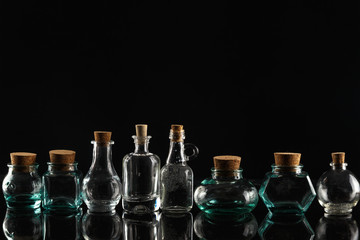 Glass bottles of different shapes and sizes on a black background.