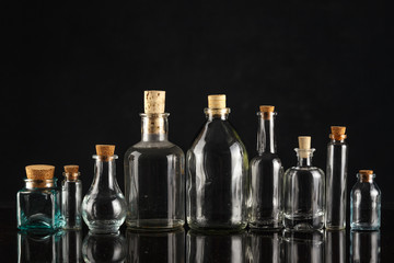 Glass bottles of different shapes and sizes on a black background.