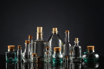 Glass bottles of different shapes and sizes on a black background.