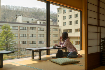 和室の窓から景色を見る女性