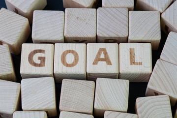Obraz premium Business goal, target and achievement list concept by cube wooden block with alphabet building the word GOAL at the center on dark blackboard background
