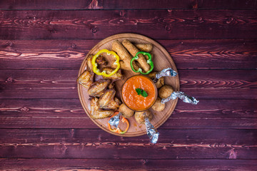 Chicken and Cheese Set for beer. Chicken wings, cheese sticks and cheese balls with bright vegetable sauce. On the cutting board and wooden background.