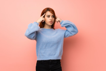 Young redhead woman over pink background having doubts and thinking