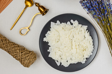 Soy wax, wick, cap, lavender - ingredient for handmade candles on black plate and white background. Flat lay. Top view. Сandle making