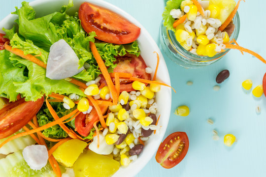 Fresh vegetable salad, tomato, potato head, corn salad, carrot, cucumber, taro bean, self-made food. Concept for a delicious and healthy meal. Blue background, top view, intimate. - image