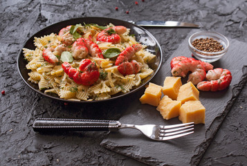 Macaroni with shrimp and cheese slices with stylish Cutlery on black background. Italian cuisine. The concept of healthy eating.