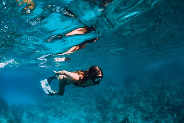 Young woman freediver with fins swim underwater ocean