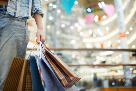 Close-up Of Unknown Woman In Jeans Carrying Shopping Bags In Mall, She Doing Shopping Alone