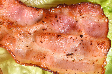 Fried bacon on lettuce leaves for a delicious breakfast. Close-up