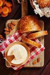 Cheese camembert or brie with bagette, nuts and dried apricots served on wooden board from above