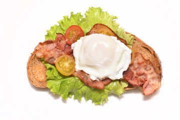 Bread and fried bacon and fried egg on lettuce and cherry tomatoes for a delicious breakfast. Close-up. Isolated