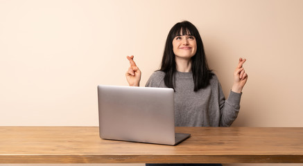 Young woman working with her laptop with fingers crossing and wishing the best