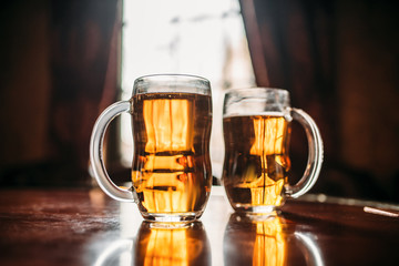 Two beer mugs on wooden bar counter, macro view