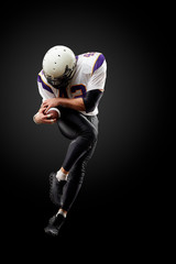 American football player in a jump with a ball on a black background © Georgii