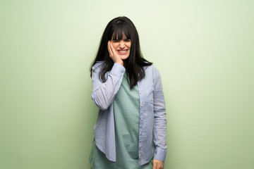 Fototapeta premium Young woman over green wall with toothache