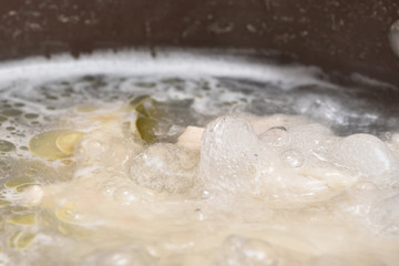 Fototapeta na wymiar Transparent and fatty broth boils and boils in a saucepan. Close-up