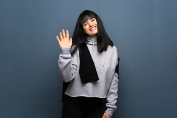 Young sport woman saluting with hand with happy expression