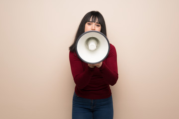 Young woman with red turtleneck shouting through a megaphone
